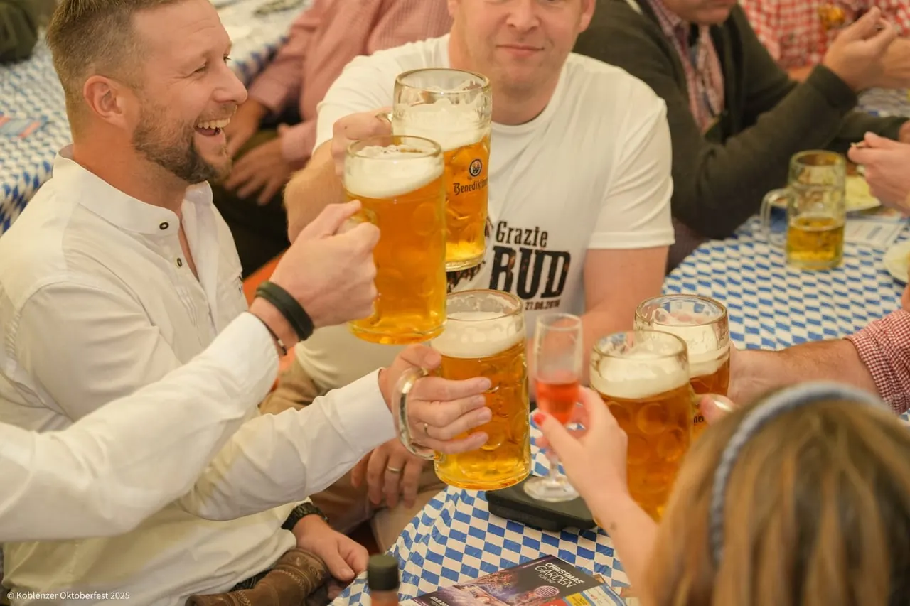 Gäste stoßen mit Maßkrügen an